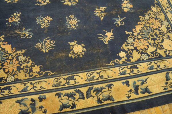 Wool hand knotted pile blue antique rectangle 1890s rug 5 Low-pile rug in navy blue and gold with traditional floral patterns resting on a light wood floor.