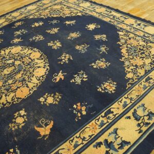 Dark blue rug with beige and peach floral motifs, a central medallion, and a thick contrasting border.