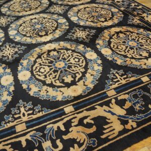 Dark rug featuring large tan and blue medallions and an ornate border on light wood flooring.