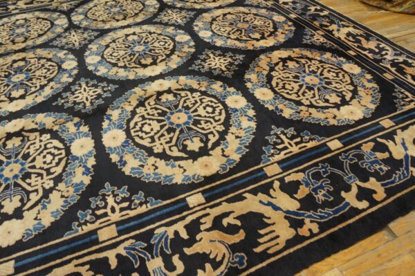 Dark rug featuring large tan and blue medallions and an ornate border on light wood flooring.