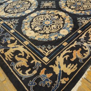 Dark navy rug with ornate beige and blue medallions and scrolling border on a distressed wood floor.