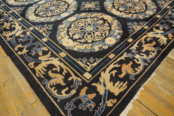 Dark navy rug with ornate beige and blue medallions and scrolling border on a distressed wood floor.