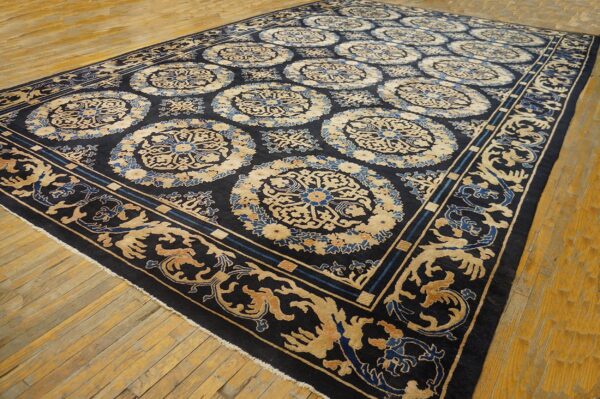Navy blue rug with repeating tan and blue medallion patterns covers wide plank wood flooring.