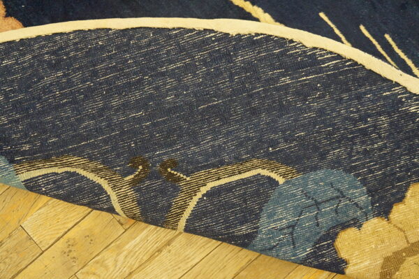 Navy blue rug backing with white weft threads and light binding curls over yellow wood planks.