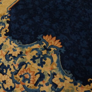 Ornate round rug with a navy floral field and a gold border featuring blue and orange scrollwork.