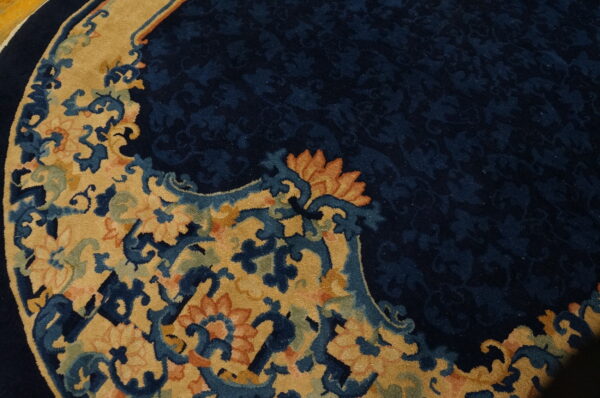 Ornate round rug with a navy floral field and a gold border featuring blue and orange scrollwork.