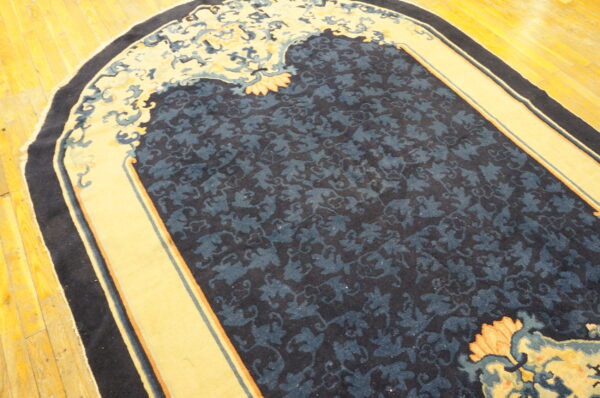 Rounded rug featuring a navy blue field with a subtle dark floral design and wide yellow borders on wood flooring.