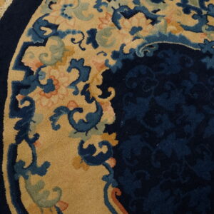 Close-up of a round navy and tan floral rug border resting on a golden hardwood floor.