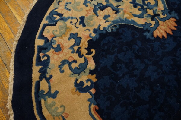 Close-up of a round navy and tan floral rug border resting on a golden hardwood floor.