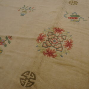 Textured cream rug detail showing scattered traditional motifs and floral medallions in pink, green, and blue.