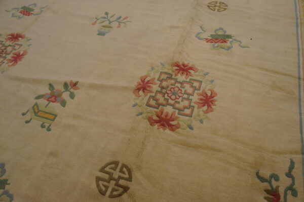 Textured cream rug detail showing scattered traditional motifs and floral medallions in pink, green, and blue.