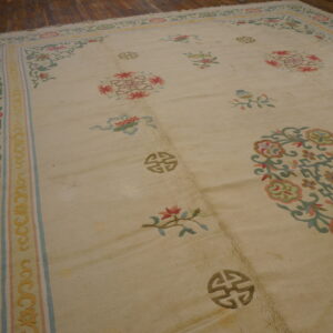 Large beige rug with pastel floral and symbolic patterns rests on dark wood planks.