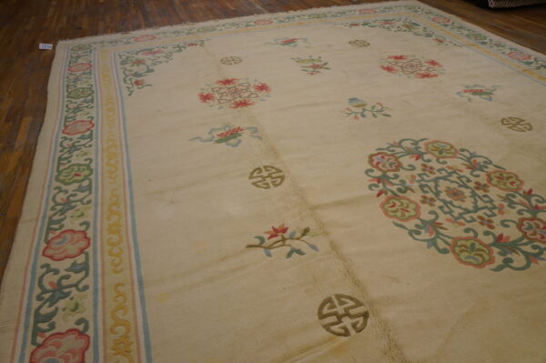 Large beige rug with pastel floral and symbolic patterns rests on dark wood planks.