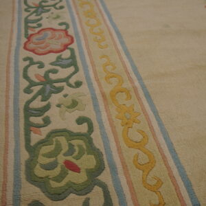 Beige rug featuring carved floral and vine borders in green, yellow, pink, and light blue on wood floors.