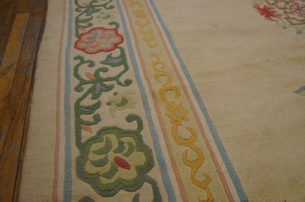 Beige rug featuring carved floral and vine borders in green, yellow, pink, and light blue on wood floors.