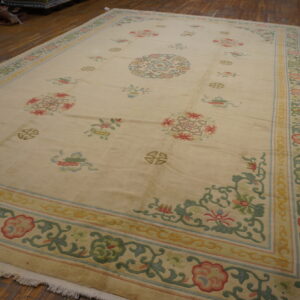 Pale cream rug with scattered pastel floral motifs and geometric medallions, resting on wide wooden planks.