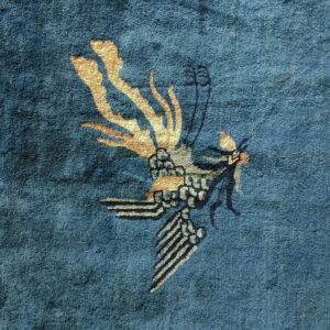 Deep blue medium-pile rug detail with a stylized gold and gray bird pattern.