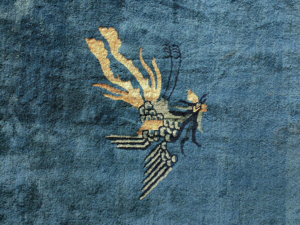 Deep blue medium-pile rug detail with a stylized gold and gray bird pattern.