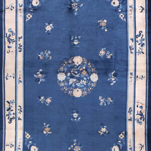 Blue rug with scattered floral motifs, a central medallion, and a contrasting wide cream border.