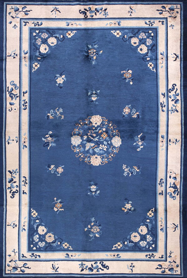 Blue rug with scattered floral motifs, a central medallion, and a contrasting wide cream border.
