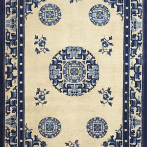 Cream rug with complex blue geometric medallions and a stylized wide blue border.