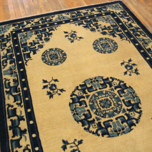 Low-pile beige rug with dark and medium blue geometric medallions on light wood plank flooring.