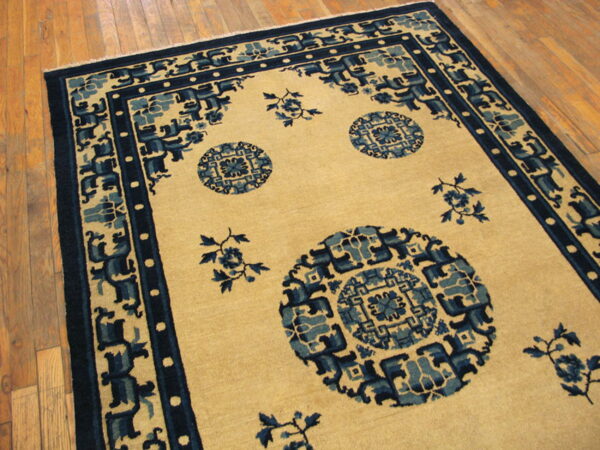 Low-pile beige rug with dark and medium blue geometric medallions on light wood plank flooring.