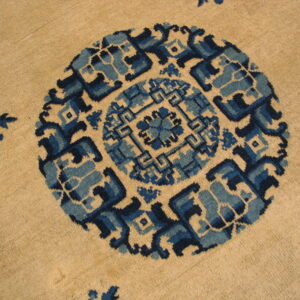 Beige rug detail featuring a large circular pattern and small floral motifs in shades of deep blue.