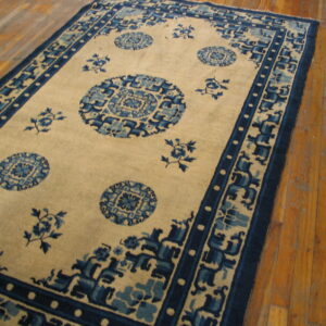 Beige and blue traditional rug with medallions and intricate borders lying on worn wood planks.