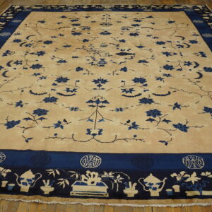 Large beige rug with sprawling blue floral motifs and complex borders featuring teapots on wood floor.