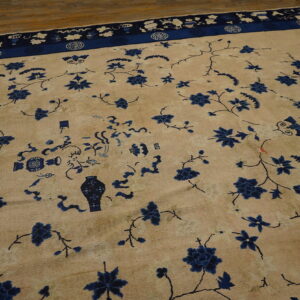 Light tan rug featuring deep blue floral sprays, vases, and a detailed symbolic border on hardwood.
