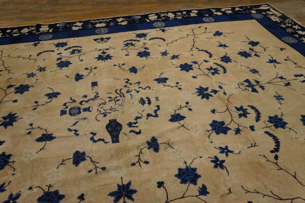 Light tan rug featuring deep blue floral sprays, vases, and a detailed symbolic border on hardwood.