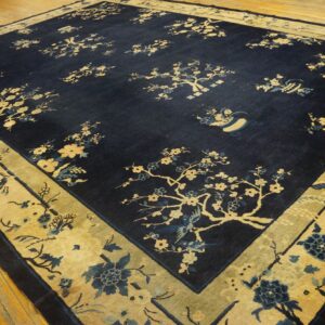 Dark navy rug featuring scattered gold and blue blossoms with a wide gold border on wood planks.