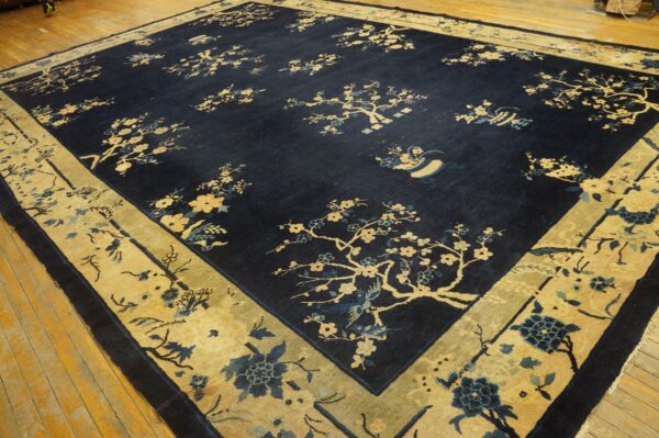 Dark navy rug featuring scattered gold and blue blossoms with a wide gold border on wood planks.