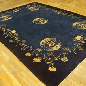Ornate dark blue rug featuring gold floral vines and large circular medallions on light wood plank floor.