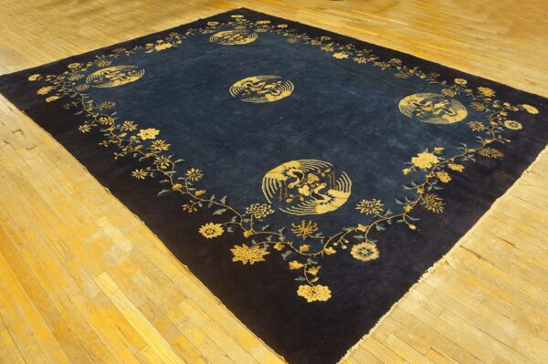 Ornate dark blue rug featuring gold floral vines and large circular medallions on light wood plank floor.