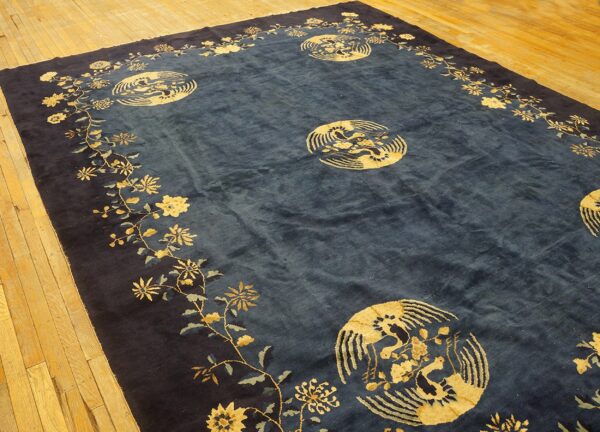 Indigo medallion rug with a gold and light blue floral border lies on wide plank hardwood flooring.