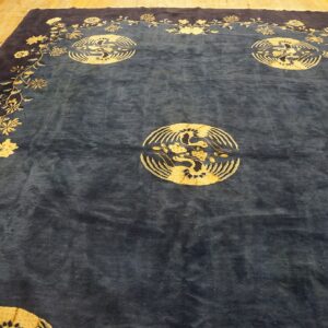 Navy blue rug with a gold floral border and three circular medallions depicting birds on wood flooring.