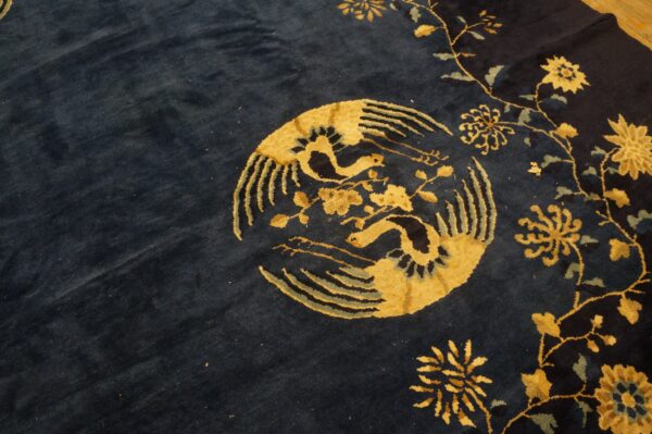 Navy blue plush rug with a gold circular bird and floral vine pattern detail.