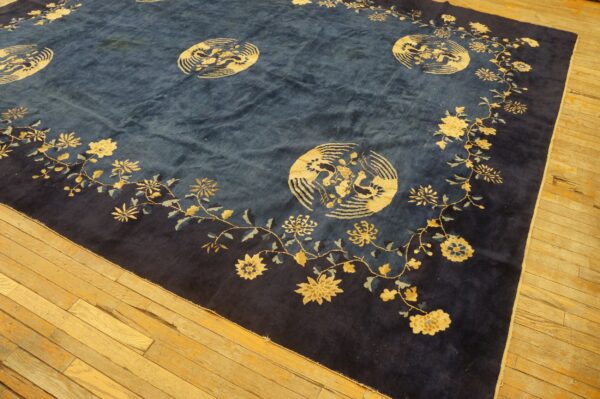 High-pile blue rug with a gold floral and bird medallion pattern lying on worn hardwood flooring.