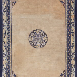 Beige rug with a central blue medallion and complex, wide navy blue and tan ornamental borders.