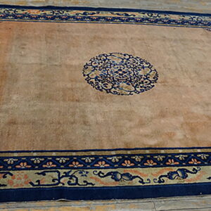 Rectangular low-pile rug featuring a peach field and intricate navy blue traditional borders on wood floors.