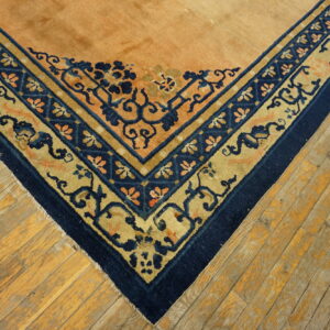 Intricate navy blue and gold bordered rug corner rests on rustic, worn wood flooring.