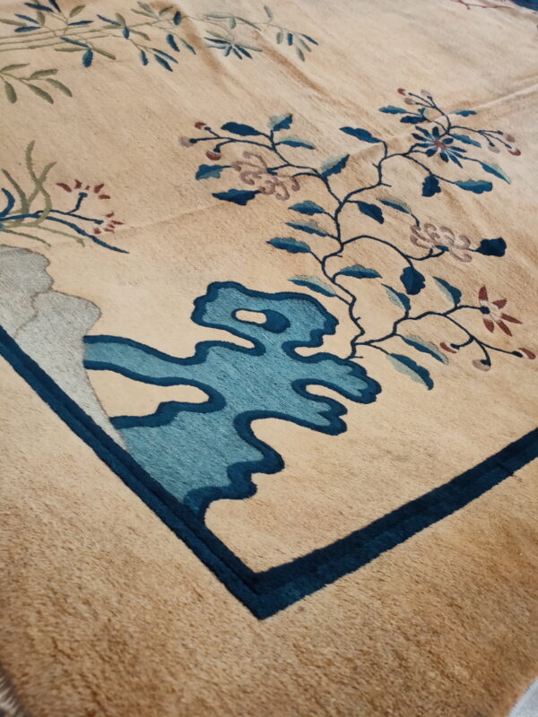 High-pile tan rug featuring stylized floral and cloud motifs in dark and light blue accents.