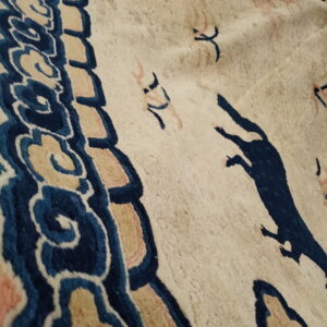 Plush cream rug detail showing indigo cloud border and scattered blue stylized running figures.