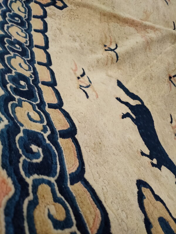 Plush cream rug detail showing indigo cloud border and scattered blue stylized running figures.