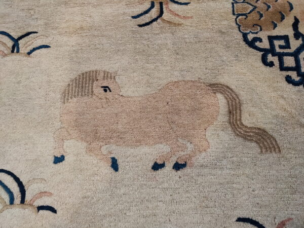 Close-up of a textured beige rug showing a tan horse pattern with blue and brown details.