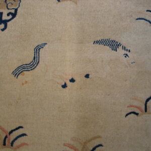A tan rug detail featuring an outlined animal and abstract motifs in navy, pink, and light gold.