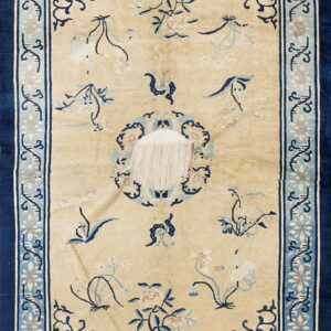 Beige rug with navy blue and light blue floral border shows severe damage exposing the white foundation.