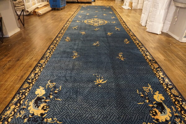 Deep blue runner rug with golden floral and medallion designs over a geometric pattern on wood flooring.